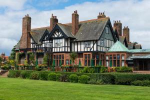 een groot zwart-wit huis met een groen gazon bij Piersland House in Troon