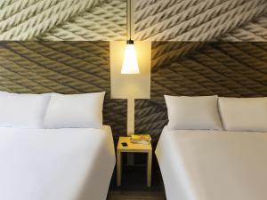 deux lits dans une chambre avec une lampe et une table de chevet dans l'établissement Ibis Mexico Tlalnepantla, à Mexico 47 autres photos