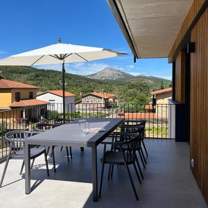 Una mesa con sillas y una sombrilla en un balcón. en Los Castaños, en La Alberca