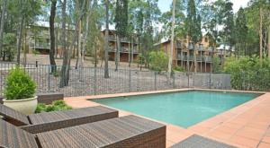 a swimming pool with two chairs and a fence at Hole-in-One Haven 2bdr Villa in Pokolbin