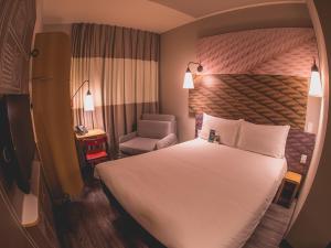 a hotel room with a bed and a chair at ibis Carlos Barbosa in Carlos Barbosa