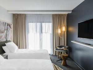 a hotel room with two beds and a flat screen tv at Mercure Hotel & Spa Bastia Biguglia in Biguglia
