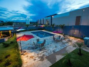 a pool with tables and umbrellas on top of a building at ibis Styles Parauapebas in Parauapebas