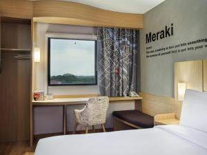 a bedroom with a desk and a bed and a window at ibis Pontianak City Center in Pontianak +31 photos