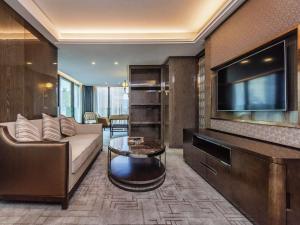 a living room with a couch and a flat screen tv at Mercure Chongqing Downtown in Chongqing