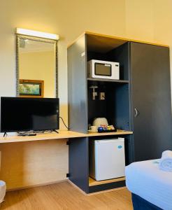 Zimmer mit einem Schreibtisch, einem Computer und einer Mikrowelle. in der Unterkunft Taree Motor Inn in Taree