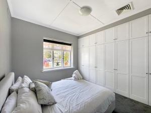 a white bedroom with a bed and a window at Peter's Central Haven in Wagga Wagga