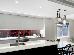 a kitchen with white cabinets and a table and chairs at Peter's Central Haven in Wagga Wagga