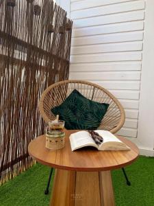 a table with an open book and a candle on it at Archipel Guadeloupéen - Entre grand balcon, piscine & lagon - Élégant cocon d'architecte 2 étoiles in Saint-François