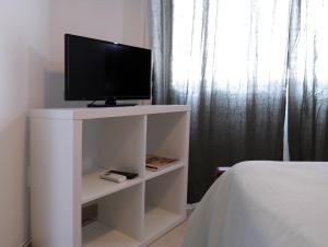 a tv on a white stand in a bedroom at Hospedaria Portuguesa in Alpiarça