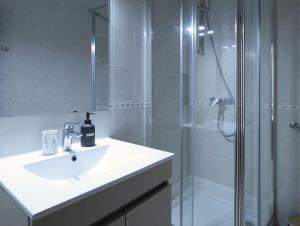 Un baño blanco con lavabo y ducha. en Hospedaria Portuguesa, en Alpiarça