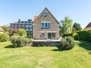 a house with a lawn in front of a building at LAuthentique in Sint-Idesbald