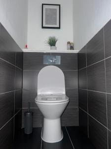 a white toilet in a bathroom with brown tiles at The Cosy Haven - 2 Bedroom house in Manchester