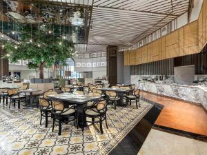 a restaurant with tables and chairs in a room at Mercure Jakarta Batavia in Jakarta
