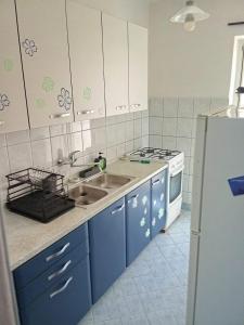 een keuken met blauwe kasten, een gootsteen en een koelkast bij Seaside secluded apartments Cove Virak, Hvar - 6969 in Gdinj