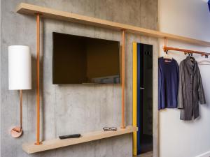 a flat screen tv on a wall with a shelf at Ibis Budget Uberlândia in Uberlândia