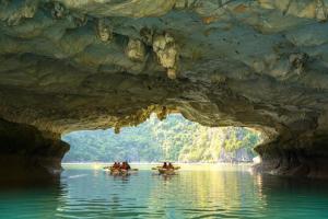 people in boats in a cave in the water at Wanderlust Station Hostel in Hanoi