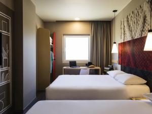 Una habitación de hotel con dos camas y un escritorio. en Ibis Torreon, en Torreón 146 fotos más