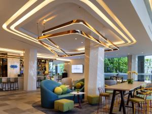 Un vestíbulo con un sofá azul, mesas y sillas. en ibis Styles Bangkok Ratchada, en Bangkok