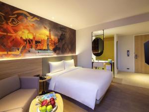 a hotel room with a white bed and a couch at ibis Styles Bangkok Ratchada in Bangkok +186 photos