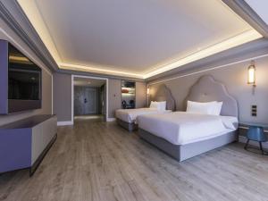 a hotel room with two beds and a tv at Mercure Xi'an Downtown in Xi'an