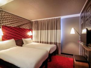 a hotel room with two beds and a tv at ibis Cahors in Cahors