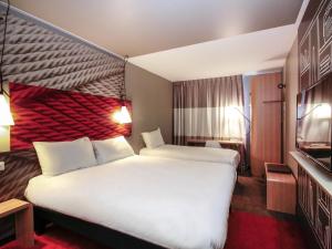 a hotel room with two beds and a television at ibis Cahors in Cahors +104 photos