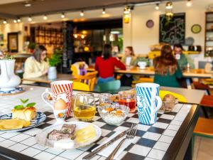 a table with plates of food and people in a restaurant at greet Hotel Beaune in Beaune
