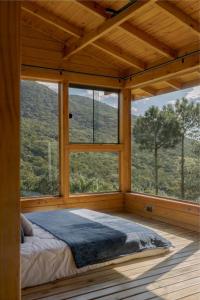 a bed in a room with a large window at Chalés Céu da Colina in Palhoça