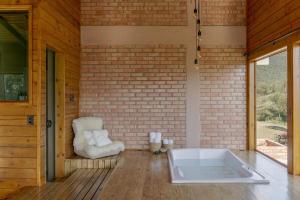 a bath tub in a room with a brick wall at Chalés Céu da Colina in Palhoça +38 photos