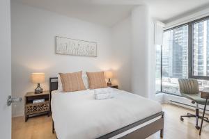 a white bedroom with a bed and a chair at Corner 2BR Old Port - Free Indoor Parking in Montreal