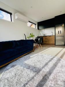 a living room with a blue couch and a kitchen at Remarkables Escape 5mins Ski Field 7mins Airport in Queenstown