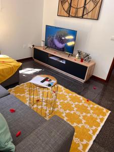 a living room with a couch and a tv at Retiro encantador em Machico - 5 min Praia e Centro A in Machico
