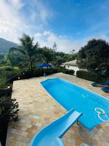 a swimming pool in a yard with a house at Chácara charmosa com piscina e natureza in Guabiruba