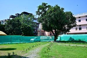 a tree in a field next to a fence at Prakriti wellness stay in Haridwār +2 photos