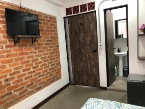 a room with a brick wall and a television and a door at La Curva Apartamentos in Cali