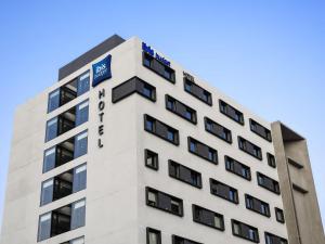 Un edificio alto y blanco con un cartel. en ibis budget Santiago Providencia, en Santiago