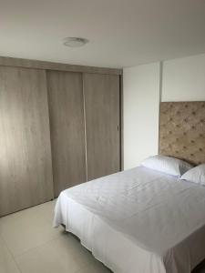 a bedroom with a large white bed and wooden cabinets at Full apartment near El Poblado in Medellín