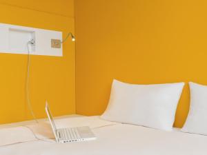 un ordenador portátil sentado en la parte superior de una cama en ibis budget Reims Parc Des Expositions, en Reims