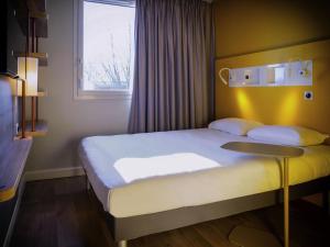 Un dormitorio con una cama grande con ventana. en ibis budget Reims Parc Des Expositions, en Reims