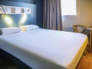 a bed with two pillows on it in a room at ibis budget Reims Parc Des Expositions in Reims