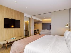 a bedroom with a large bed and a tv on a wall at Mercure Itajai Navegantes in Itajaí