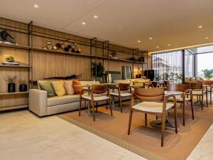 a living room with a couch and tables and chairs at Mercure Itajai Navegantes in Itajaí