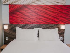 Bett mit zwei weißen Kissen und einem roten Kopfteil in der Unterkunft ibis Trujillo in Trujillo