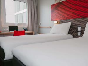 ein Hotelzimmer mit einem weißen Bett und einem Schreibtisch in der Unterkunft ibis Trujillo in Trujillo