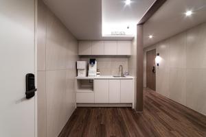 a kitchen with white cabinets and a sink and a hallway at Hi Stay Jongno in Seoul