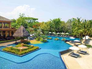 a pool at a resort with chairs and umbrellas at Mövenpick Asara Resort & Spa Hua Hin in Hua Hin