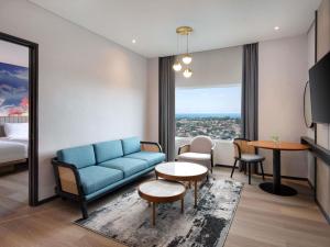 a living room with a blue couch and a table at Mercure Bengkulu in Bengkulu