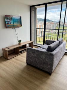 a living room with a couch and a large window at Apartamento completo cómodo con vista y todo cerca CC VIVA in Tunja
