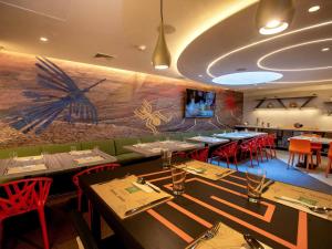 une salle à manger avec des tables et des chaises ainsi qu'une fresque murale. dans l'établissement ibis Styles Lima Benavides Miraflores, à Lima